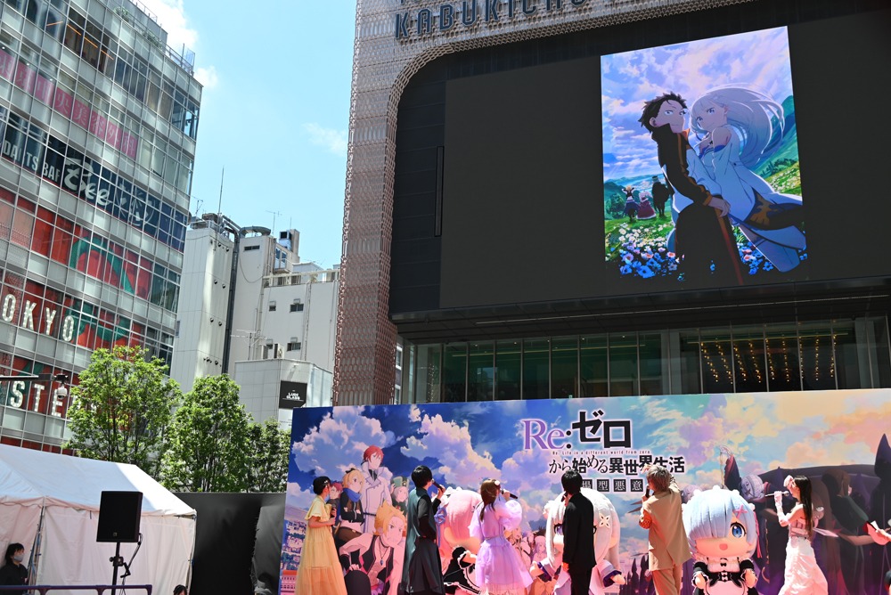 大型ビションに映し出された新たなキービジュアルを見上げるキャストたち。