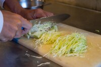 広告の制作担当者がキャベツの千切りに挑戦する様子。
