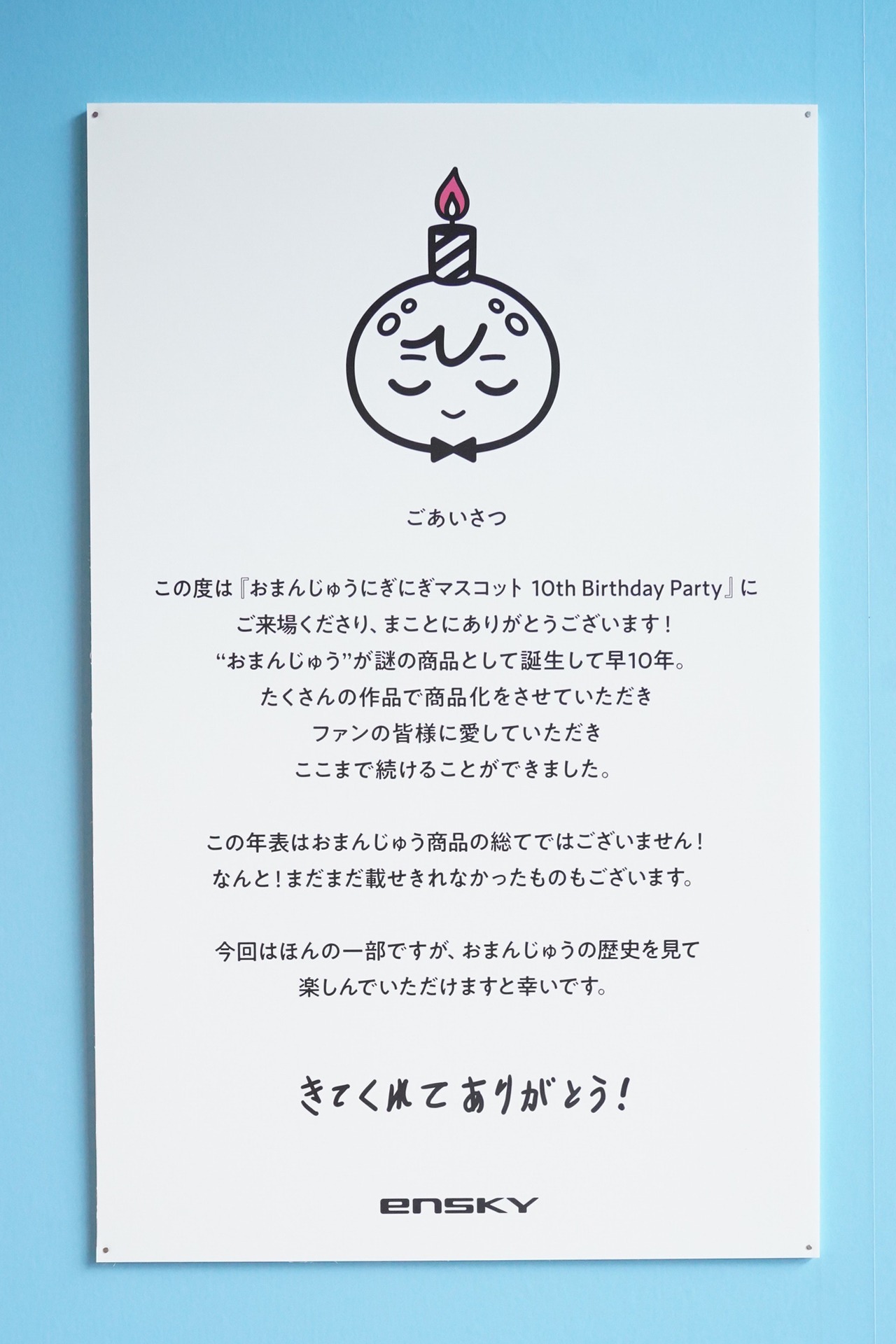 「おまんじゅうにぎにぎマスコット10th Birthday Party POP UP SHOP」に掲出された「ごあいさつ」。ちなみに「10さいまんじゅう」のロゴや、この掲示物にある「きてくれてありがとう！」などの文字は、10歳のおまんじゅうが書いたもの……？かもしれないとのこと。