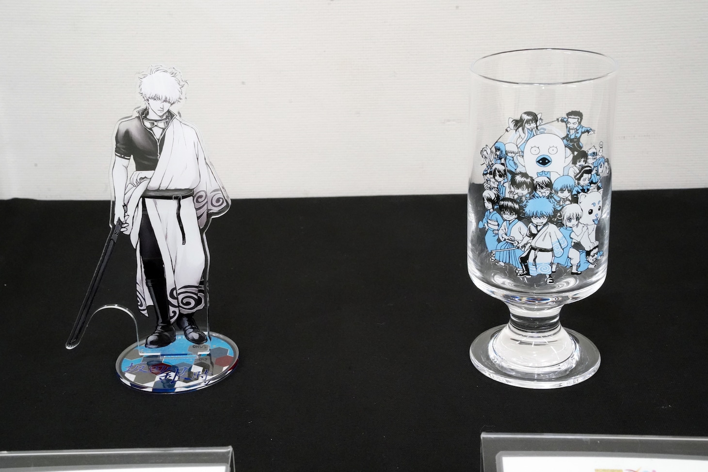 「生誕20周年記念 銀魂展 ～はたちのつどい～」で販売される「箔入りアクリルフィギュア　［坂田銀時］」とフロートグラス。