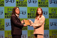 「ハネチンとブッキーのお子さま診療録」関係者として、表彰盾を受け取るコアミックスの小林恭子氏。