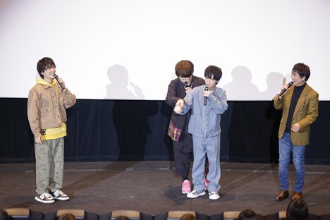 小林千晃の背後にまわって手を取り、書道を教えるジャスチャーを行う緑川光。