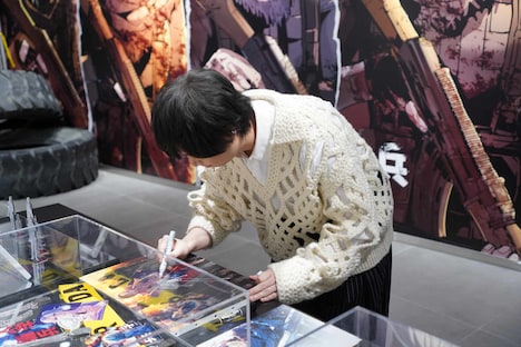 グッズにサインをする斉藤壮馬。