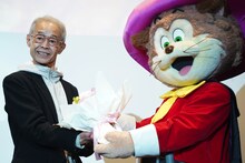 ペロから花束を渡される西尾大介監督プロデューサー。