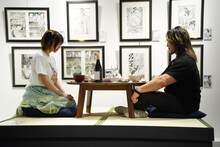 刃牙と勇次郎の食卓を再現するえなこ（左）と棚橋弘至（右）。来場者も同じようにこの食卓に座り、写真撮影をすることが可能だ