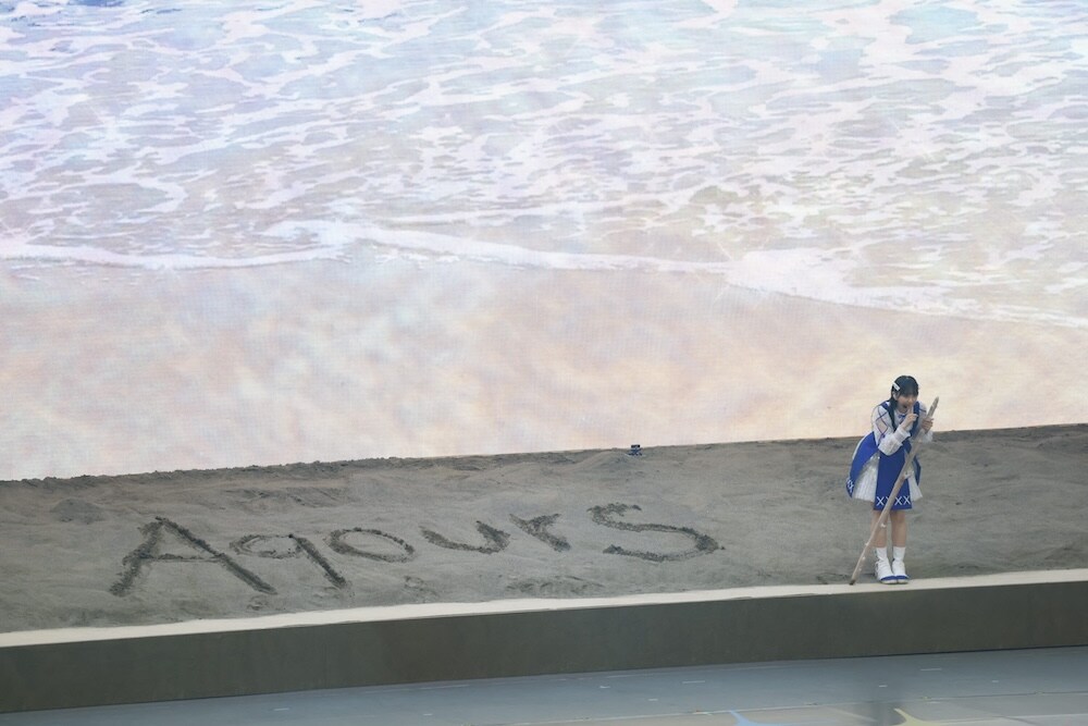 砂浜に「Aqours」の文字を書く小宮有紗 - 「ラブライブ