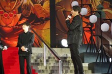 登壇者の後ろに作られたセットを称賛する小西克幸（右）