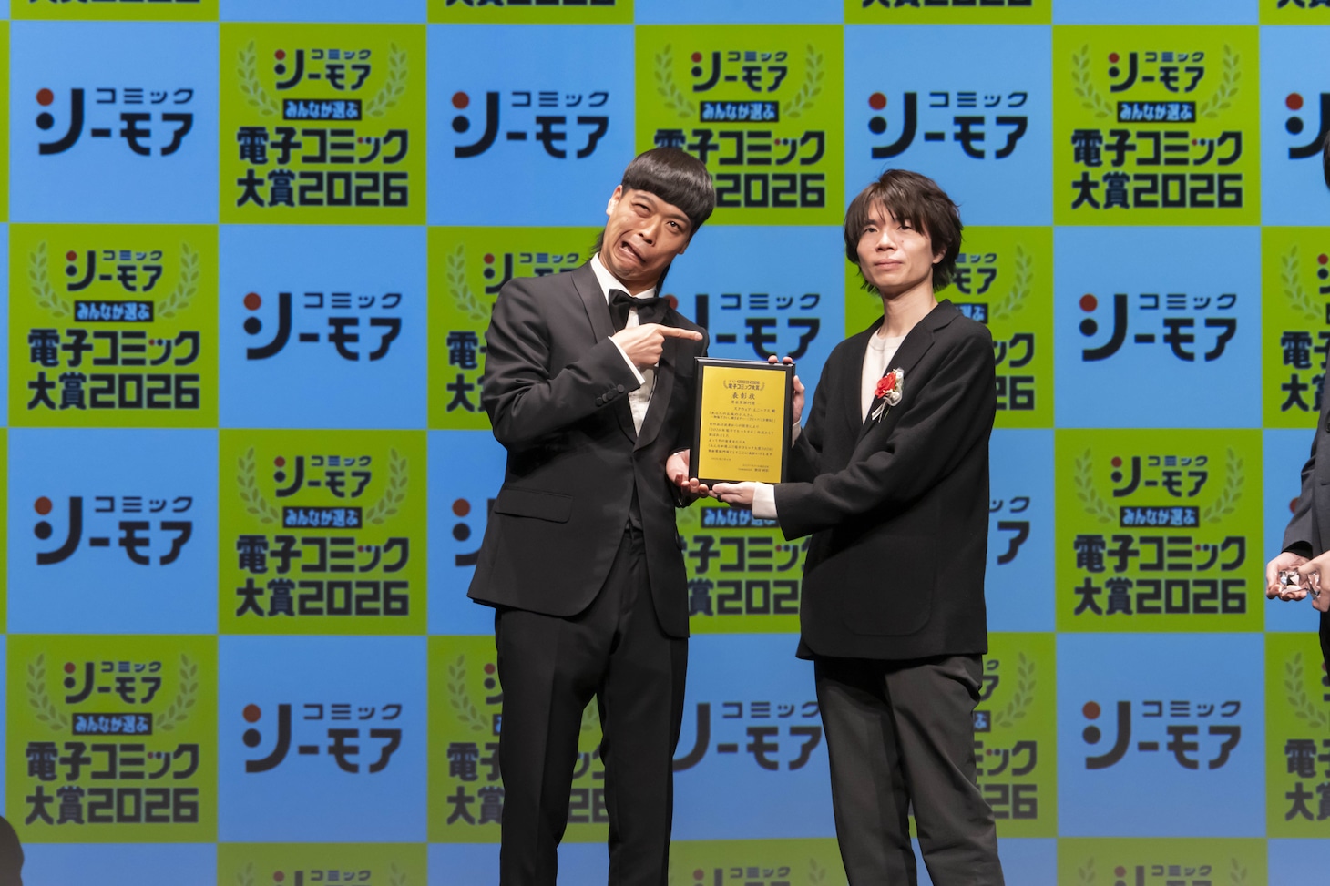 異世界部門受賞作「あなたのお城の小人さん ～御飯下さい、働きますっ～」への受賞シーン。右はスクウェア・エニックスの岡本洸平