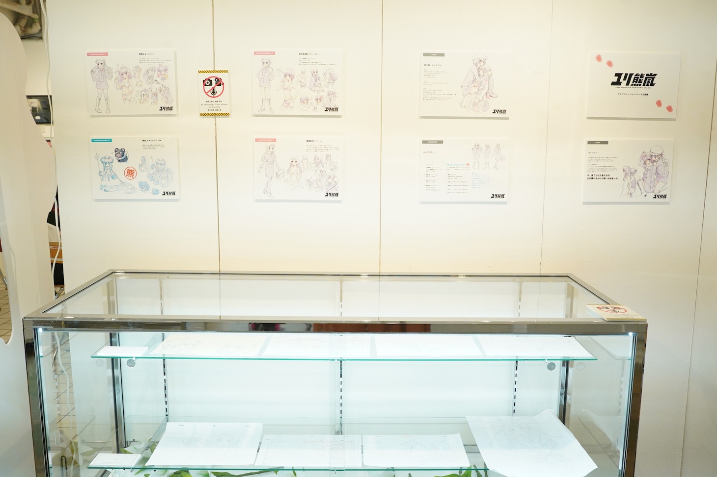 「ユリ熊嵐展-10th anniversary-」会場内の様子。壁面には制作前の企画書、ケース内には原画が展示されている