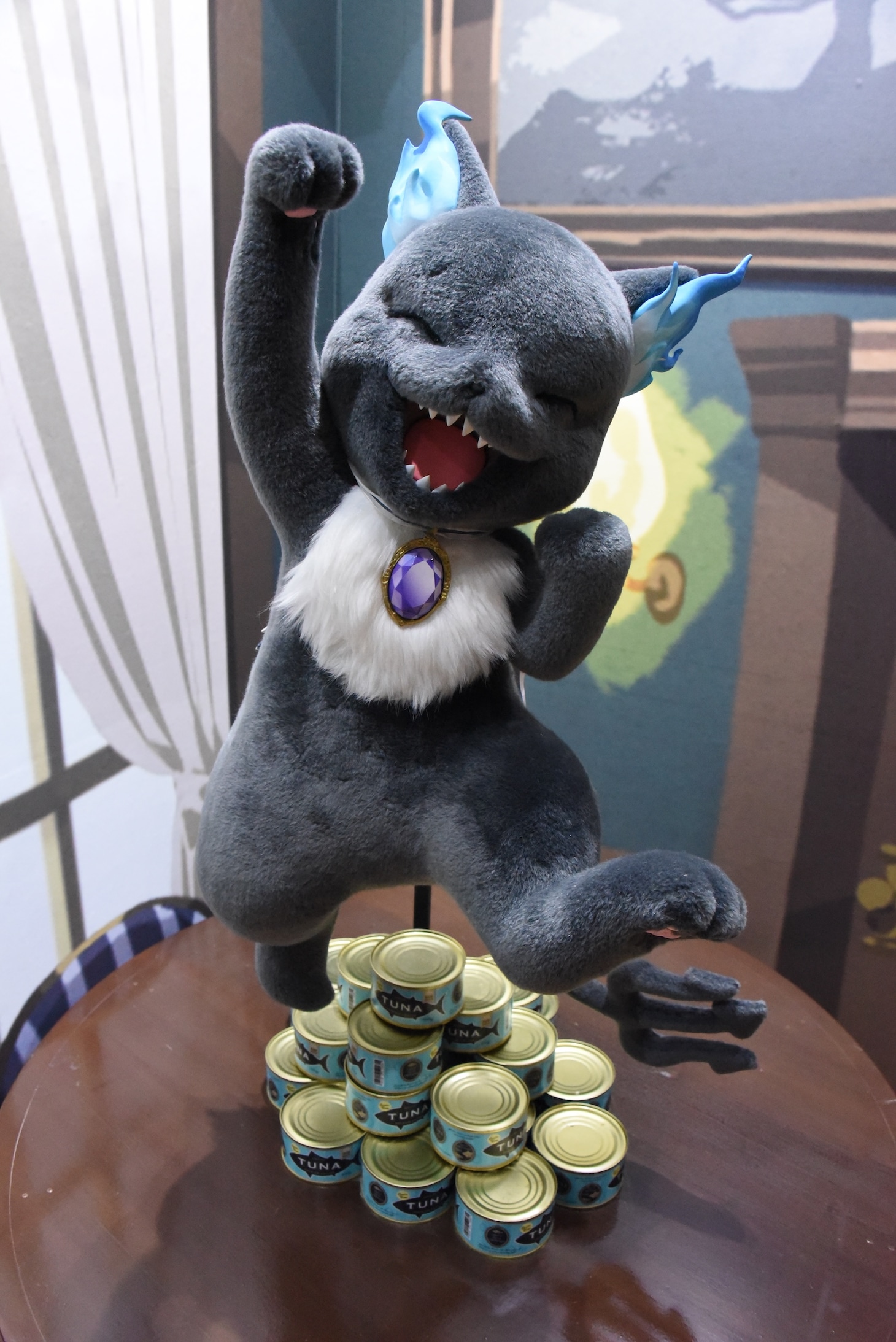 「ディズニー ツイステッドワンダーランド展 Seasonal Memories」より、オンボロ寮の再現展示に登場したグリム。大量のツナ缶に笑顔を見せている