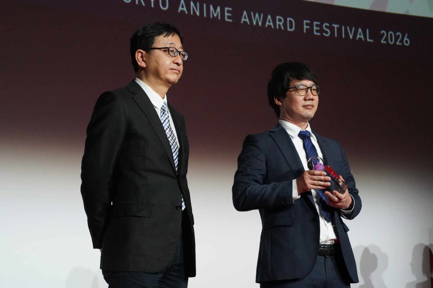 左からプレゼンターの田中千義、山本二三の代理で登壇した山本鷹生氏