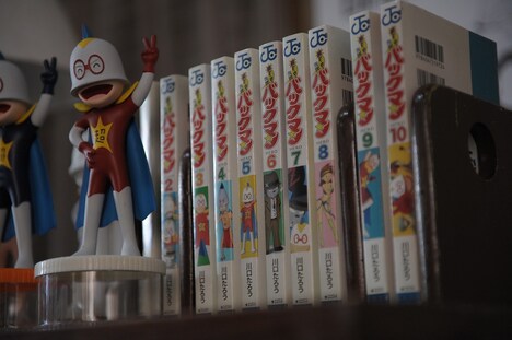 川口たろう作「超ヒーロー伝説 バックマン」も部屋の片隅に並んでいる。(c)2015映画「バクマン。」製作委員会