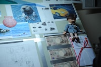 平丸はデスクにお札を飾るほどのお金好き。(c)2015映画「バクマン。」製作委員会