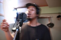 リリックを手にマイクの前に立つ「THE COCKPIT」のワンシーン。(c)Aichi Arts Center, MIYAKE Sho