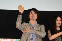 脇を隠して手を振る斎藤工。