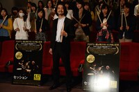 ドラムスティックを持ち、試写会参加者と記念撮影をする金子ノブアキ。