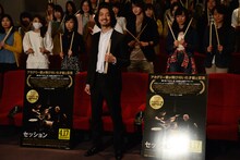 ドラムスティックを持ち、試写会参加者と記念撮影をする金子ノブアキ。