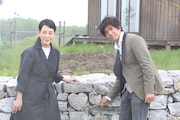 左から樋口可南子、佐藤浩市。石塀へハート型に作られた石をはめ込む様子。