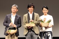 美瑛町の町民から贈られたアスパラガスを手にする朝原雄三監督（左）、佐藤浩市（中央）、樋口可南子（右）。