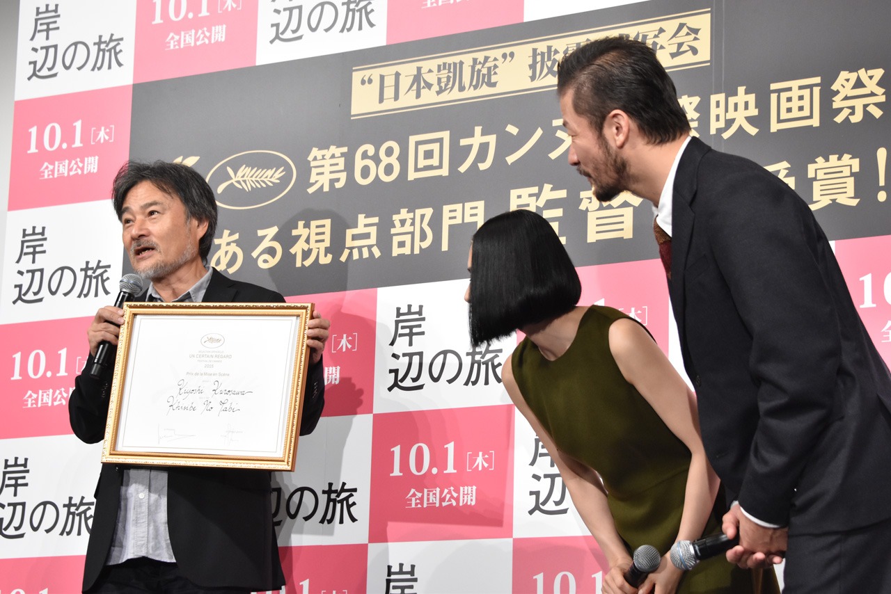 左から賞状の解説をする黒沢清、しげしげと賞状を眺める深津絵里と浅野忠信。