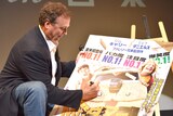「帰ってきたMr.ダマー バカMAX!」のポスターにサインをするボビー・ファレリー。