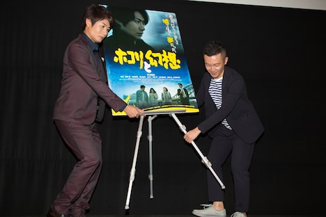 フォトセッションのため、鈴木聖史(右)とともに自らポスターの位置を調整する戸次重幸(左)。