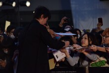 ファンに差し出された色紙にサインする新井浩文。