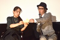 安藤玉恵（左）に、自身がイラストを手がけたステッカーを見せるリリー・フランキー（右）。