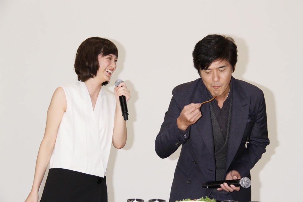 本田翼（左）と、彼女が作ったザンギを試食する佐藤浩市（右）。