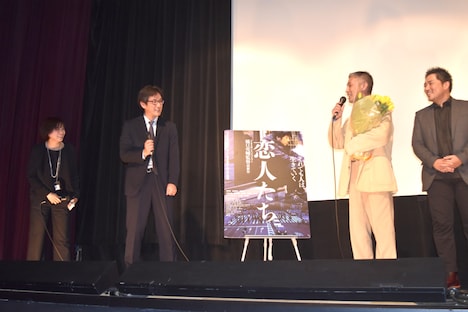 プロデューサーの深田誠剛（左から2人目）に花束を渡され、喜ぶ橋口亮輔（左から3人目）。