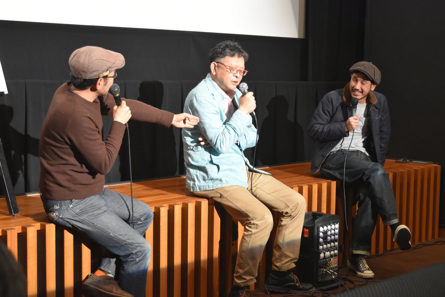 越川道夫（左）と大崎章（中央）から、自身の魅力を熱弁されて照れる渋川清彦（右）。