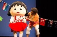 まる子（左）のずれたたすきを直してあげるパパイヤ鈴木（右）。