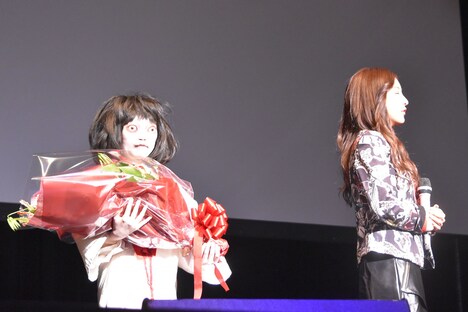 目を閉じる板野友美（右）の背後に歩み寄る“のぞきめ”ことスズ役の石井心愛（左）。