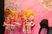 会見の様子。フォトセッション前に身を寄せ合うキュアブルーム、キュアピーチ、キュアメロディ、キュアハート、キュアフローラ。