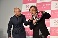観客に借りたうちわで「環」の漢字の意味を解説する武田鉄矢（右）と、サポートする宇野祥平（左）。