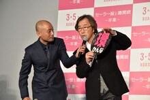 観客に借りたうちわで「環」の漢字の意味を解説する武田鉄矢（右）と、サポートする宇野祥平（左）。