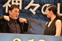 舞台挨拶中に汗だくになりジャケットを脱いでしまい、写真撮影の際に慌ててそれを着るピエール瀧（左）。