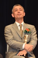 スピーチ中の篠原篤を見守ろる橋口亮輔。