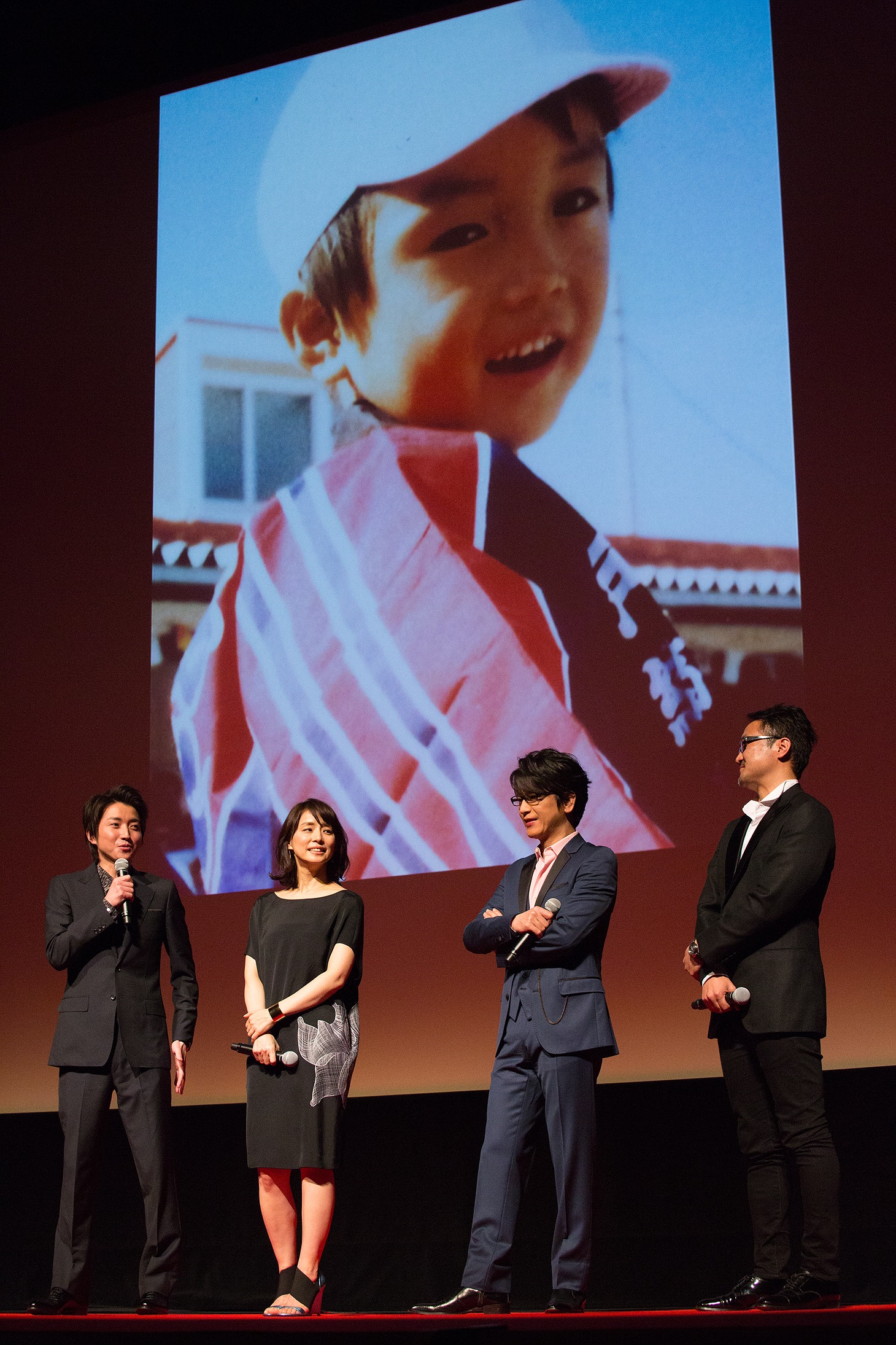 藤原竜也（左）の幼少時の写真をバックにトークを繰り広げる登壇者たち。