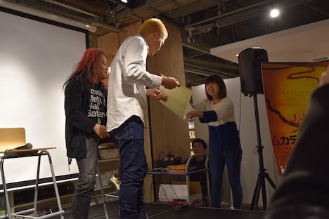 “ムカデ人間卒業証書”を受け取る北村昭博(中央)。