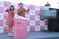 池袋の通行人に向かって、ビジョンを通して手を振る二階堂ふみ（左）と山崎賢人（右）。