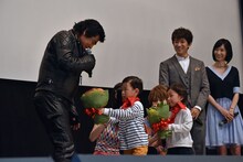 2人の子供が藤岡弘、に花束を渡す様子。