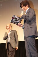 横山秀夫（左）からプレゼントされた「64-ロクヨン-」英語翻訳版を眺める佐藤浩市（右）。