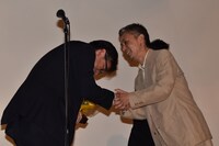 固く握手をする深田誠剛（左）と橋口亮輔（右）。