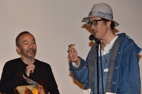 金獅子のトロフィーの説明をするリリー・フランキー（右）と、笑みを見せる塚本晋也（左）。