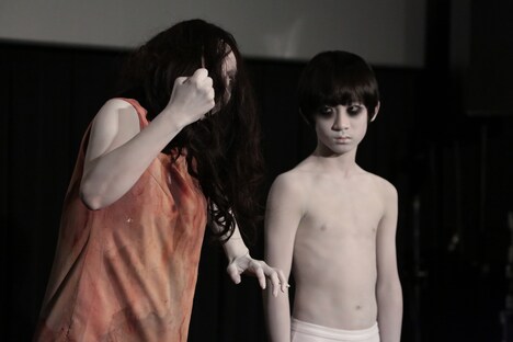 ガッツポーズを披露する伽椰子（左）と、それを冷めた目で見つめる俊雄（右）。