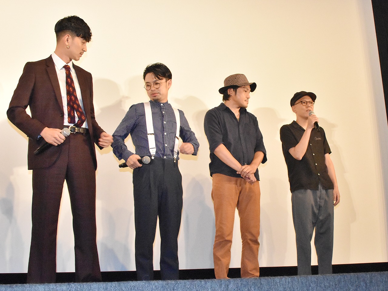 「ディアスポリス－異邦警察－」DVD発売記念イベントより、真利子哲也（右端）がコメント中に浜野謙太（左から2番目）のサスペンダーをいじる松田翔太（左端）。