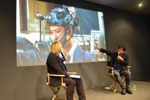 ヘッドセット型カメラを装着する岡田将生のメイキング写真を見ながら解説する大友啓史（右）。