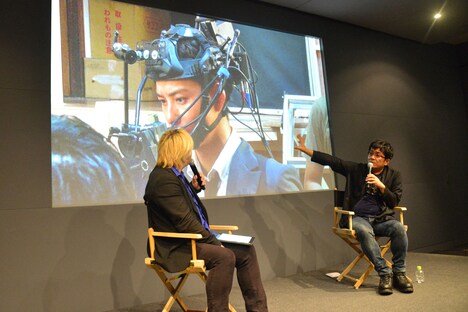 ヘッドセット型カメラを装着する岡田将生のメイキング写真を見ながら解説する大友啓史(右)。