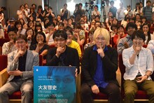 「秘密 THE TOP SECRET」のタイトルにちなみ“秘密”ポーズをする大友啓史（中央左）、津田大介（中央右）、観客。